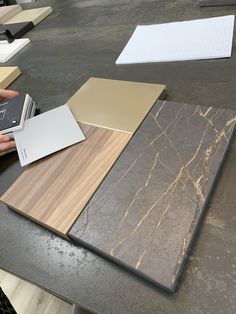 a person holding a cell phone next to different types of flooring materials on a table