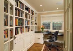 a home office with white bookcases and lots of books