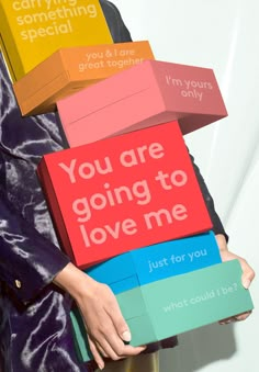 a woman holding several colorful boxes that say you are going to love me, just for you