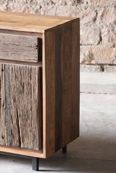 an old wooden cabinet with metal legs and wood grains on the front, against a brick wall