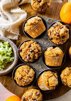 several muffins are sitting in a muffin tin next to some pumpkins