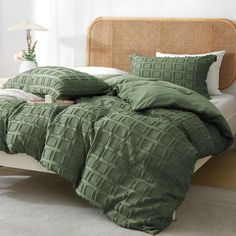 a bed with green comforters and pillows on it