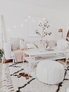 a living room with white furniture and rugs on the floor, including a coffee table