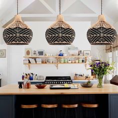 three lights hanging from the ceiling above a kitchen island with stools and counter top