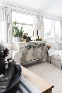 a living room filled with white furniture and christmas decorations on top of it's windowsill