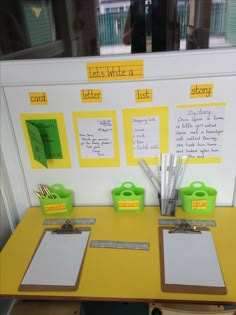 a yellow desk topped with lots of papers and clipboards next to a whiteboard