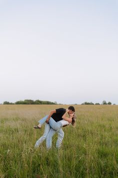 a man and woman are kissing in the middle of a field with tall green grass