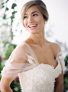 a woman in a wedding dress smiling at the camera