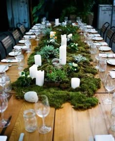 the table is set with candles and moss