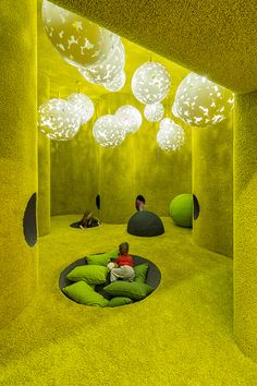 a child sitting on a bean bag chair in a room with lights hanging from the ceiling