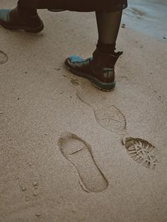 a person standing in the sand with their foot prints