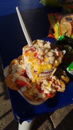 a blue table topped with a bowl filled with food next to tortilla chips