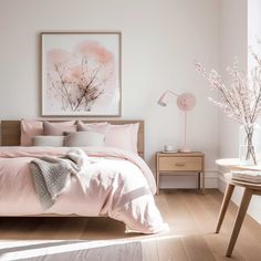 a bedroom with white walls and pink bedding in the corner, along with a painting on the wall