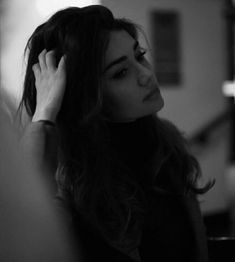 a black and white photo of a woman holding her hair up to her head with one hand