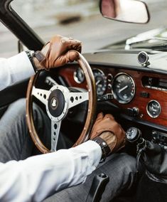 a man sitting in the driver's seat of a car with his hands on the steering wheel