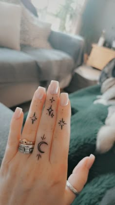 a woman's hand with an arrow and crescent tattoo on her left ring finger