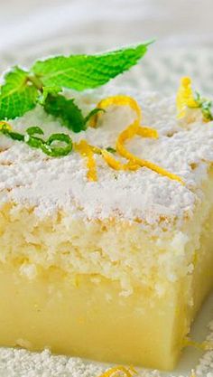 a slice of lemon cake on a plate with mint garnish and powdered sugar