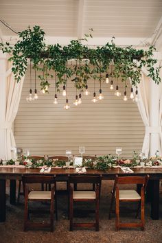 the table is set up with greenery and hanging lights