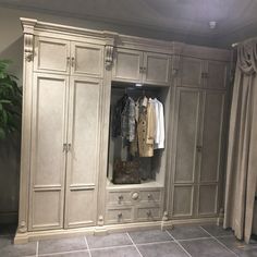 a large white closet filled with lots of clothes and coat hangers next to a potted plant