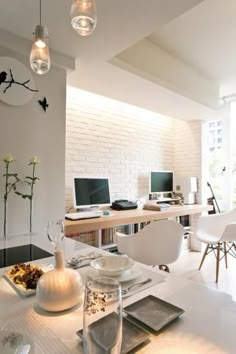 a room with white walls and tables, chairs, desks and computer screens on the wall