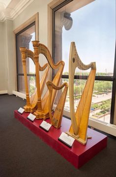 three wooden harps are on display in front of a large window with a view