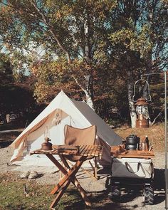 a tent set up in the middle of a field with an outside table and chairs