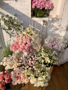 many different types of flowers in vases on the floor next to a wall and window