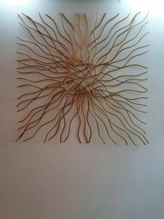 there is a wall sculpture made out of branches on the side of a wall with lights above it