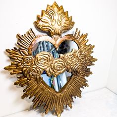 a heart shaped mirror hanging on the side of a wall next to a white wall