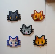 four perler beads are arranged in the shape of cats and kittens on a white wall