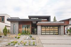 a modern house with stone and wood accents in the front yard, along with landscaping