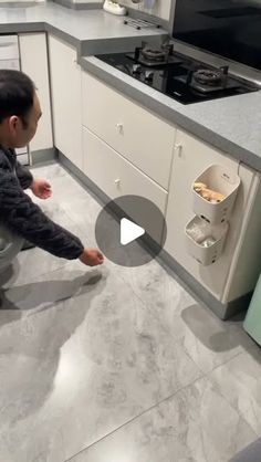 a man kneeling down in front of a stove top oven next to a kitchen counter