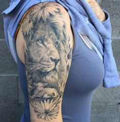 a woman with a lion and flowers tattoo on her arm is posing for the camera