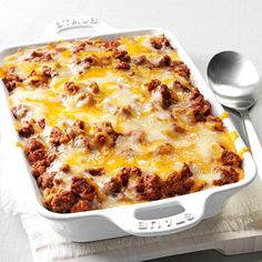 a casserole dish with meat and cheese in it on a white tablecloth