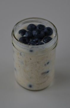 a glass jar filled with oatmeal and blueberries