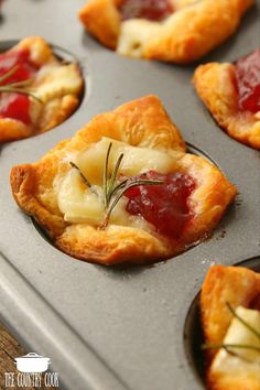 small pastries in a muffin tin filled with jelly and cheese, garnished with rosemary