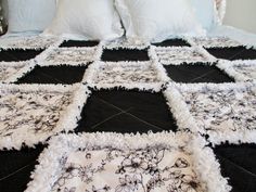 a black and white quilted bedspread with flowers on the edges, along with two pillows