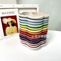 a stack of multicolored ceramic bowls sitting on top of a table next to a book