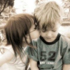 two young children sitting next to each other with their faces touching one another's cheek