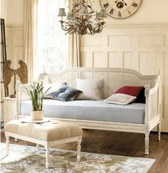 a living room filled with furniture and a large clock on the wall above it's windows