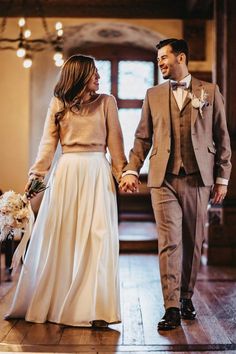 a bride and groom holding hands walking down the aisle at their wedding ceremony in an old building