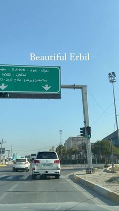 cars are driving down the street under a beautiful ebrii sign in abu, united arab emirates