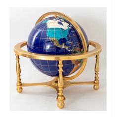 a small blue and gold globe sitting on top of a wooden stand with two legs