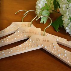 three wooden clothes pins with personalized names on them and some flowers in the background