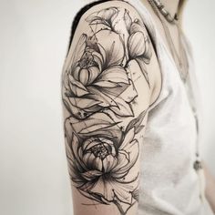 a woman's arm with black and white flowers on the left side of her arm