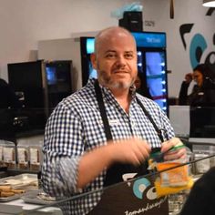 a man standing in front of a counter with some items on it and people behind him