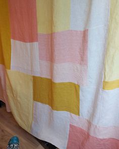 a cat sitting on the floor in front of a curtain with multicolored squares