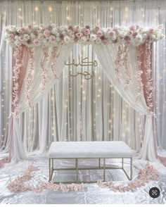 a wedding stage decorated with flowers and white drapes, pink roses on the side