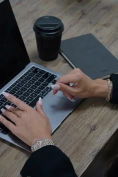 a woman is typing on her laptop while sitting at a table with a coffee cup