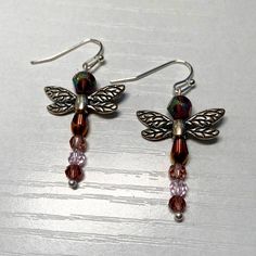 a pair of dragonfly earrings with multicolored beads and silver earwires